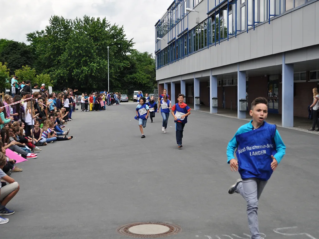Läufer auf der Strecke, Kinder sitzen am Rand.